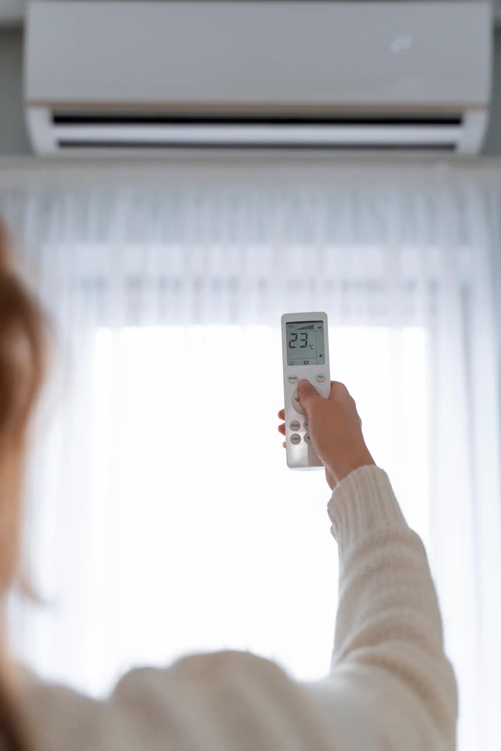 woman-holding-remote-start-heater woman holding a remote pointing it at a white air conditioner