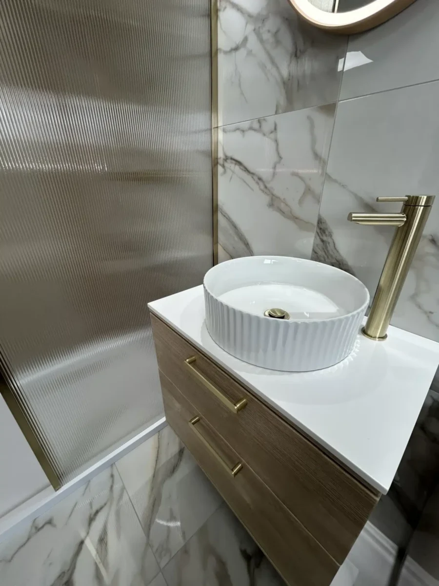 modern bathroom with white marble flooring and backing tiles, modern sink with gold chrome fixings